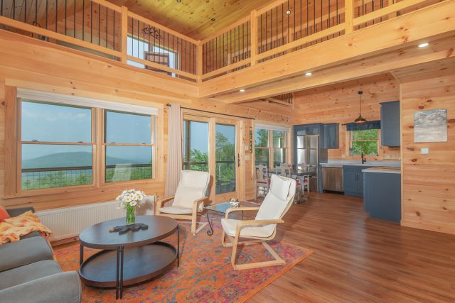 Bright open-plan living room with large windows overlooking Maine mountains
